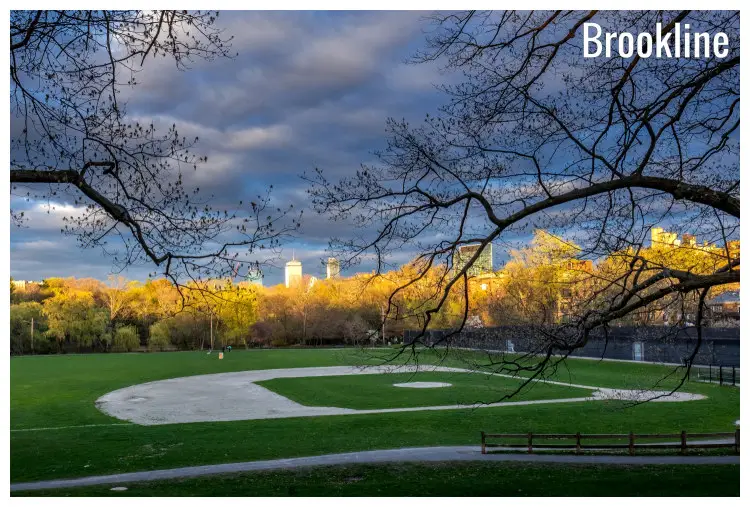 A small league field in Brookline, Massachusetts, overlooking bright yellow trees in the fall, behind the cityscape of Boston A small league field in Brookline, Massachusetts, overlooking bright yellow trees in the fall, behind the cityscape of Boston