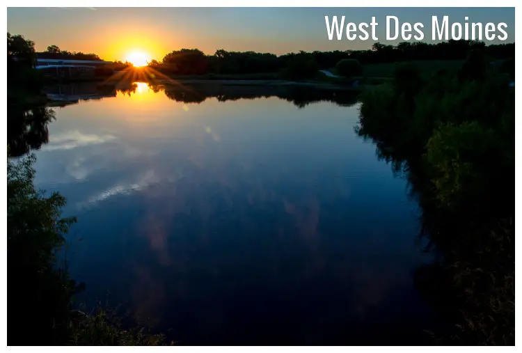 The bright red and yellow sun rising over the horizon in West Des Moines, Iowa, casting the glow over the famed City Campus Pond and trees
