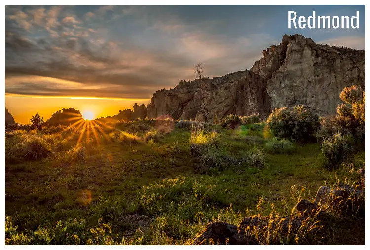 The bright yellow eye and rays of the setting sun seen over the hilly and rocky scape in the Smith Rock State Park in Redmond, Oregon