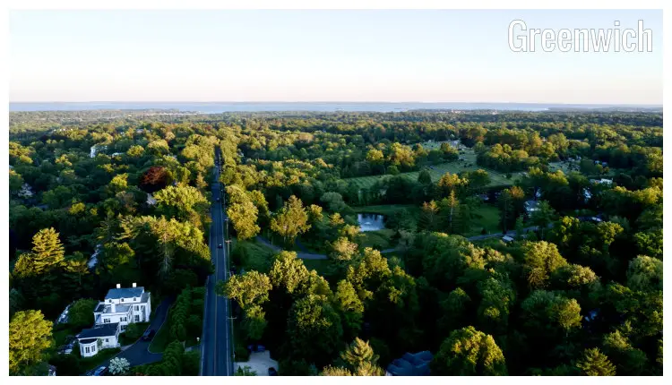The straight road of North Street cutting through the green leafy suburbs of the scenic Greenwich City in Connecticut