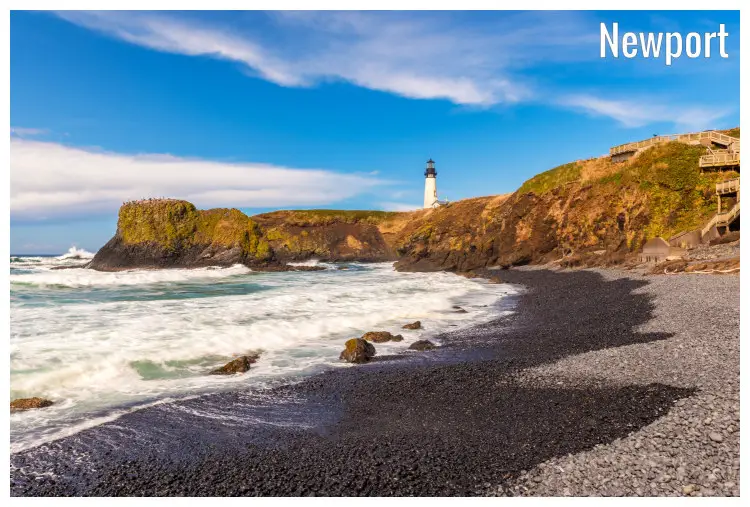 Light waves wash to the pebbly and stony shores overlooking the high rock cliffs holding the iconic Yaquina Head Lighthouse in Newport, Oregon