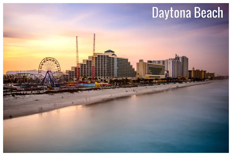 The white sandy shores of Daytona Beach in Florida, with a distant view of a funfair and the cityscape The white sandy shores of Daytona Beach in Florida, with a distant view of a funfair and the cityscape
