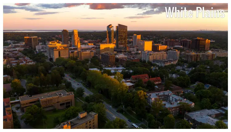 Yellow rays from the setting sun shining upon the buildings in White Plain, New York