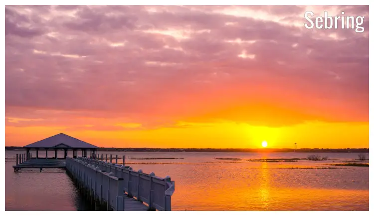 The colorful sky with bright yellow and red rays from the setting sun spread over the water in Sebring, Florida
