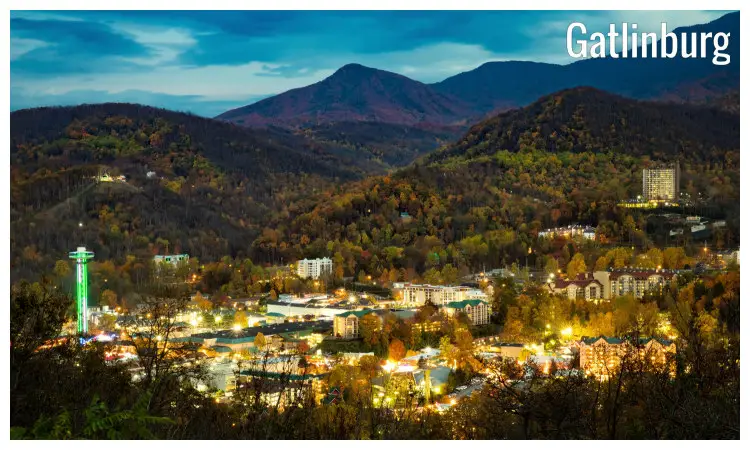 The city of Gatlinburg, Tennessee, with bright night neon lights, with scenic fall foliage seen on the nearby hills