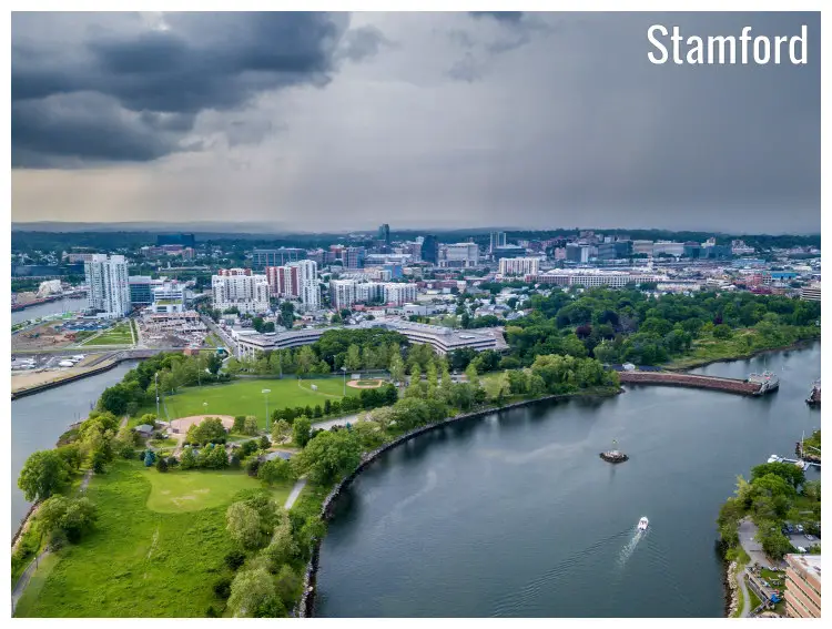 A wide aerial scenic cover shot over downtown Stamford, Connecticut, with two rivers and weighty rain clouds in the sky above A wide aerial scenic cover shot over downtown Stamford, Connecticut, with two rivers and weighty rain clouds in the sky above