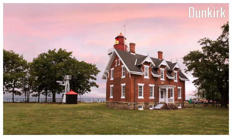 The Dunkirk Lighthouse, New York, standing alone in this vast field amid trees, with the light at the top, overlooking the dark Lake Eerie The Dunkirk Lighthouse, New York, standing alone in this vast field amid trees, with the light at the top, overlooking the dark Lake Eerie