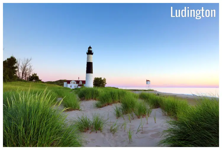 A big field with grass and sand next to the tall and colorful Sable Point Lighthouse in the scenic Ludington State Park, Michigan A big field with grass and sand next to the tall and colorful Sable Point Lighthouse in the scenic Ludington State Park, Michigan
