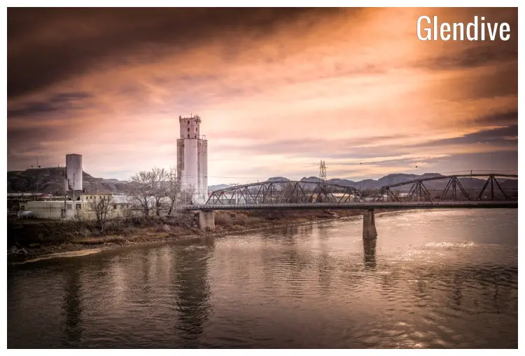 The calm Yellowstone River running under a bridge through a vast industrial landscape, in Glendive, Montana The calm Yellowstone River running under a bridge through a vast industrial landscape, in Glendive, Montana