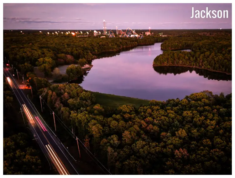 Golden and brown tree leaves, car lights on the freeway, lights from the afar fun park, and the calm lake in Jackson, New Jersey Golden and brown tree leaves, car lights on the freeway, lights from the afar fun park, and the calm lake in Jackson, New Jersey