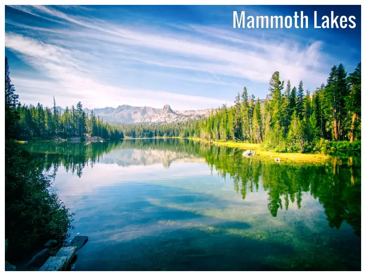 Perfect water reflections of trees, rocks, and distant mountains in the clear water of Mammoth Lakes, California