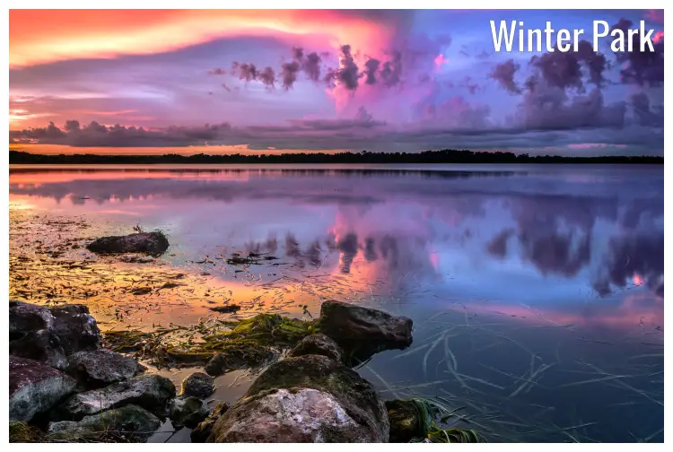 Rocks on the shores of Lake Baldwin in Winter Park, Florida, and the dramatic colorful sky above in a perfect mirror image in the calm lake water