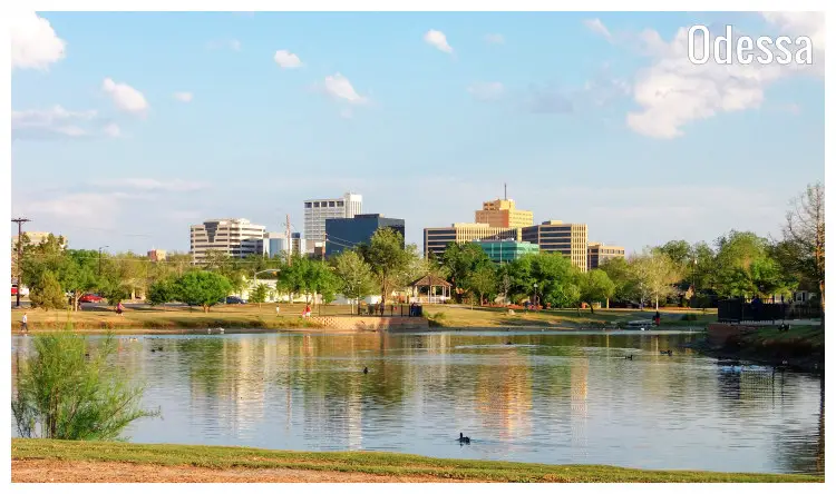 A striking image of a calm pond and a scenic garden park on its other side, behind the buildings of the city of Odessa in Texas A striking image of a calm pond and a scenic garden park on its other side, behind the buildings of the city of Odessa in Texas