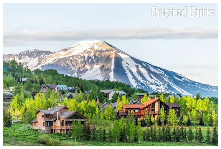 Scenic wooden holiday homes amid trees and great scenery in a village in Crested Butte, Colorado, a view of the snowy Mount Butte in the back Scenic wooden holiday homes amid trees and great scenery in a village in Crested Butte, Colorado, a view of the snowy Mount Butte in the back