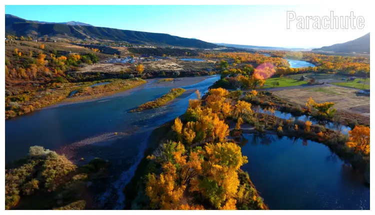 Gorgeous brown and golden trees in the fall, seen in the wide river with a far view of rocks and hills in Parachute, Colorado Gorgeous brown and golden trees in the fall, seen in the wide river with a far view of rocks and hills in Parachute, Colorado
