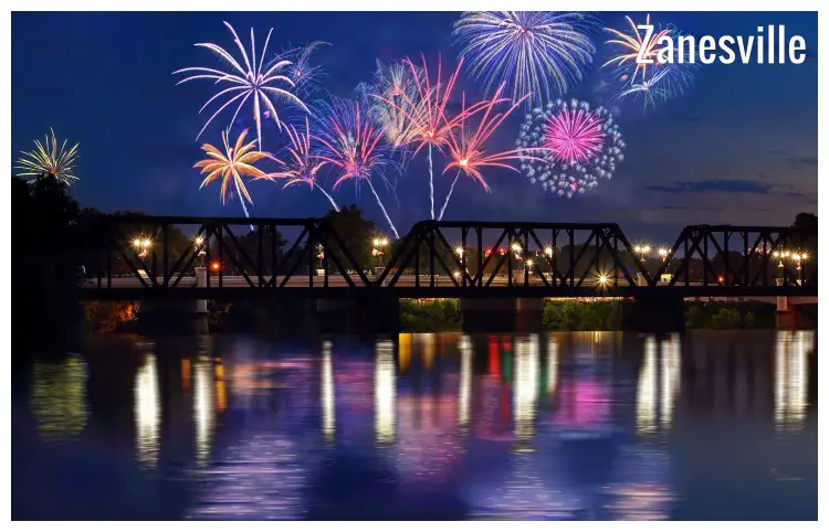 Colorful fireworks seen in the sky above a large bridge on the Muskingum River in Zanesville, Ohio, during celebrations on Independence Day