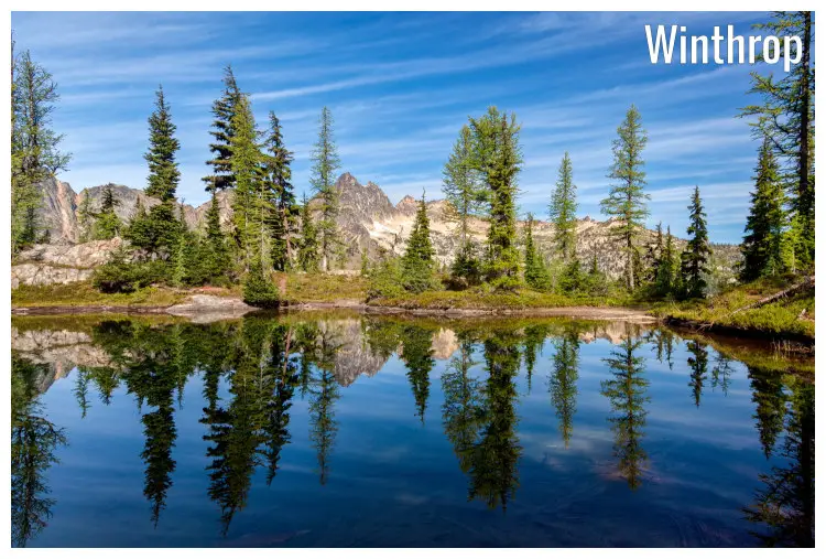A mirror view in the blue water of Blue Lake of the trees and rock cliffs nearby, in Winthrop, Washington