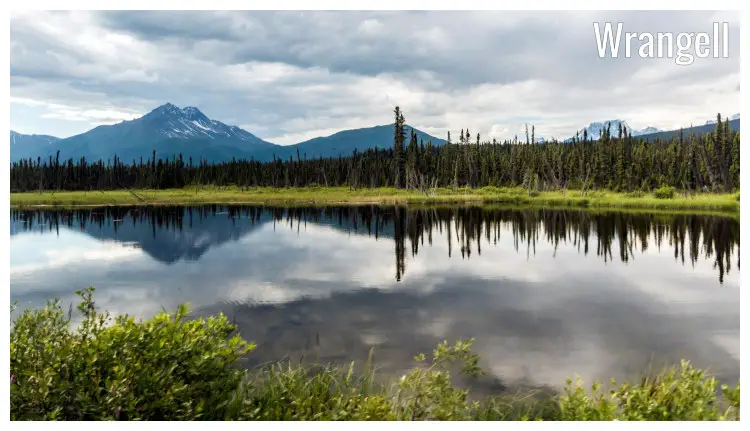 A stunning view of Wrangell within St Elias National Park in Alaska, featuring a landscape of water, fields, and distant snowy mountains A stunning view of Wrangell within St Elias National Park in Alaska, featuring a landscape of water, fields, and distant snowy mountains