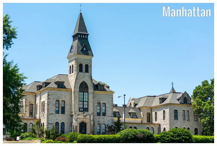 A large building with a high tower in the scenic setting of the Kansas State University in Manhattan A large building with a high tower in the scenic setting of the Kansas State University in Manhattan