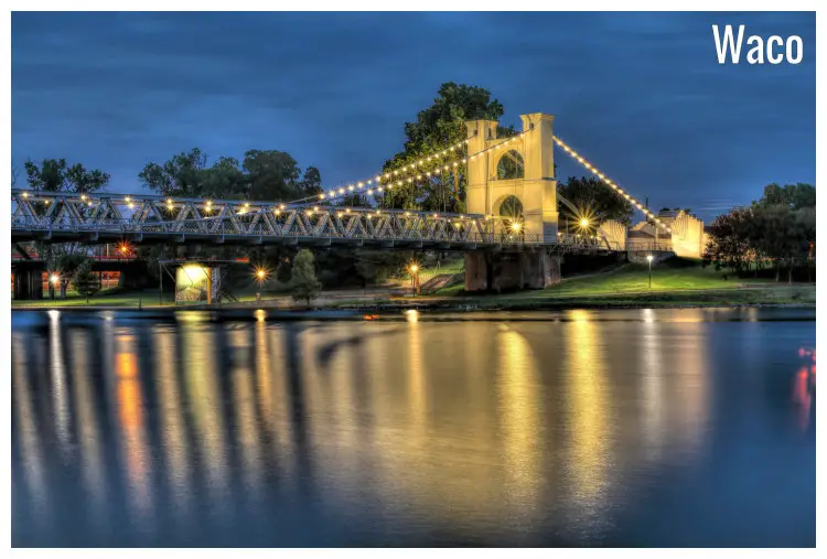 The high Waco Suspension Bridge crossing on the large Brazos River in the Indian Spring Park in Waco, Texas The high Waco Suspension Bridge crossing on the large Brazos River in the Indian Spring Park in Waco, Texas