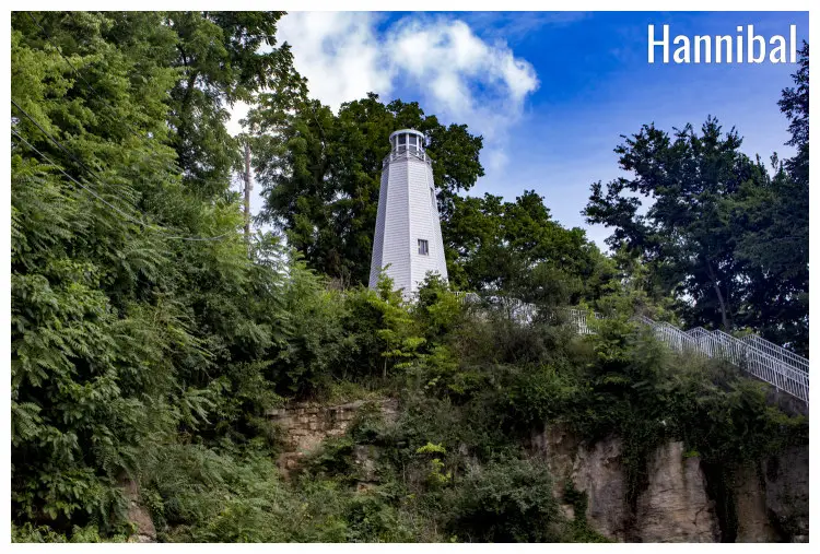 The stunning Mark Twain Memorial Lighthouse stands tall in white among the surrounding rocks and greenery in Hannibal, Missouri The stunning Mark Twain Memorial Lighthouse stands tall in white among the surrounding rocks and greenery in Hannibal, Missouri