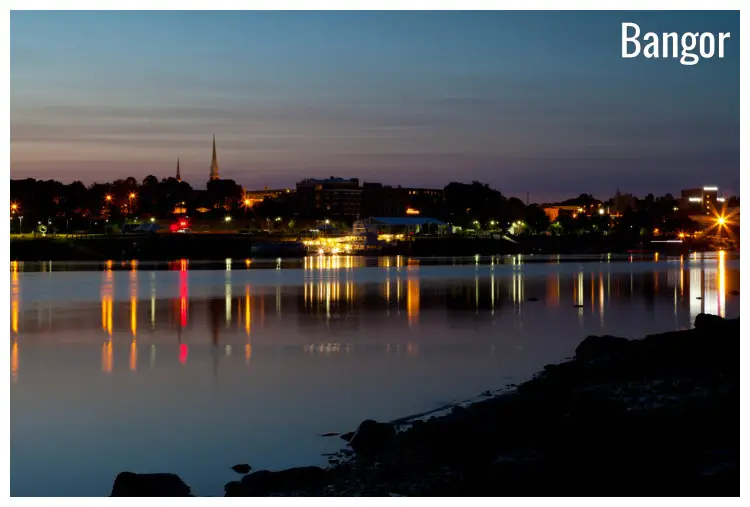 The neon-lit city of Bangor, Maine, at night with the clear sky and neon lights reflected in the water below The neon-lit city of Bangor, Maine, at night with the clear sky and neon lights reflected in the water below