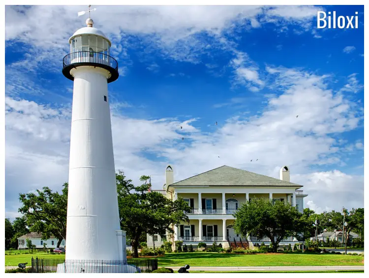 A tall and white iconic landmark of a lighthouse and other houses in this scenic field of clean lawns in Biloxi, Mississippi A tall and white iconic landmark of a lighthouse and other houses in this scenic field of clean lawns in Biloxi, Mississippi