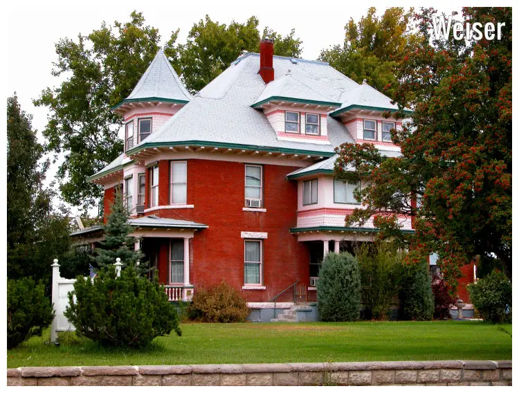 A colorful mansion built and designed in the Queen Anne style set in a scenic lawn with beautiful and colorful trees in Weiser, Idaho
